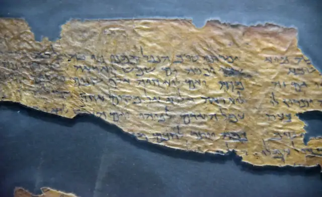 Fragmentary zwoje z Qumran, starożytne teksty pisane hebrajskimi literami na pożółkłym papirusie, ukazujące wieki historii.