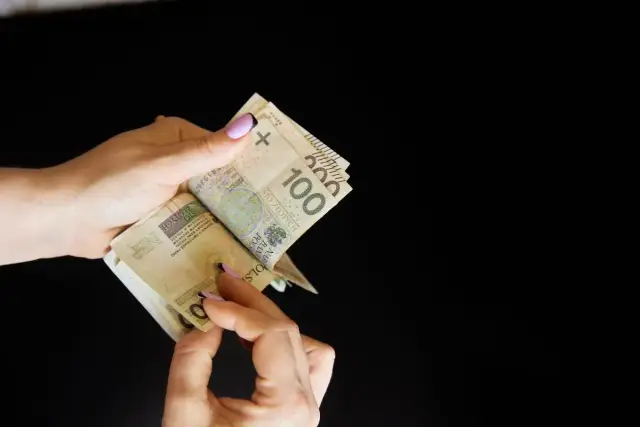 Dłonie liczą banknoty 100 zł. Może to być związane ze zniesieniem współwłasności i podziałem majątku.