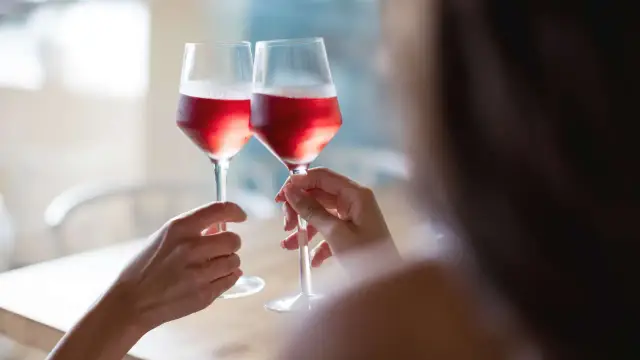 Dwie osoby wznoszą toast różowym winem. To wyjaśnia, dlaczego wino różowe nie powstaje z mieszania białego z czerwonym.