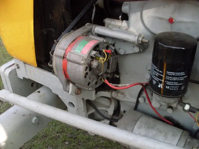 Szczegółowy widok alternatora i filtra oleju w ciągniku C-330. Pokazuje, jak podłączyć alternator do C-330, z widocznymi przewodami i mocowaniami.
