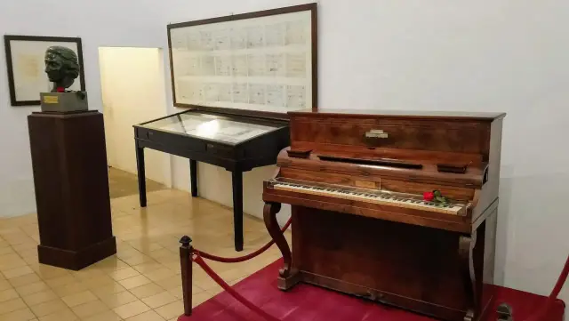 Muzyczne pamiątki po Chopinie na Majorce: fortepian, popiersie kompozytora i jego nuty.