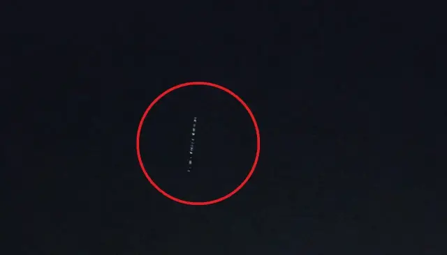 Linia jasnych punktów na ciemnym niebie, przypominająca pociąg satelitów Starlink.