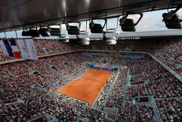 Widok z góry na pełny stadion tenisowy podczas meczu WTA 500. Na korcie ziemnym toczy się zacięta gra, a trybuny wypełnia liczna publiczność.
