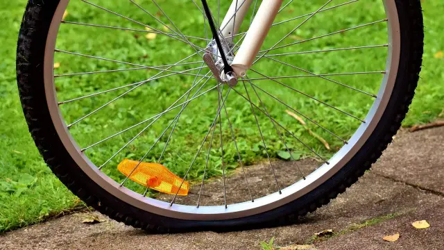 Płaska dętka rowerowa leży na trawie, obok pomarańczowego odblasku.