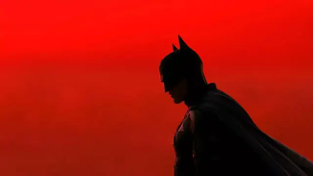 Sylwetka Batmana na tle czerwonego nieba. Nowe batman filmy zapowiadają mroczną przygodę.