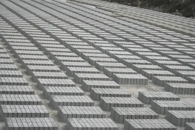 Ogromne pole betonowych bloczków ułożonych w równe rzędy. Trudno oszacować, ile bloczków betonowych na palecie, ale jest ich tysiące.