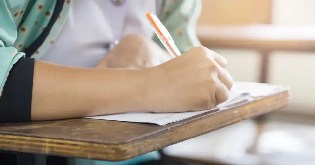 Uczeń pisze na kartkówce, zastanawiając się, czy edukacja zdrowotna będzie obowiązkowa.