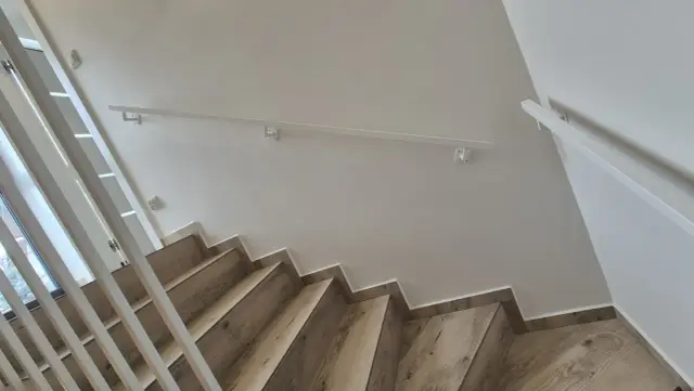 Nowoczesne balustrady wewnętrzne z białymi poręczami i drewnianymi stopniami tworzą elegancką przestrzeń.