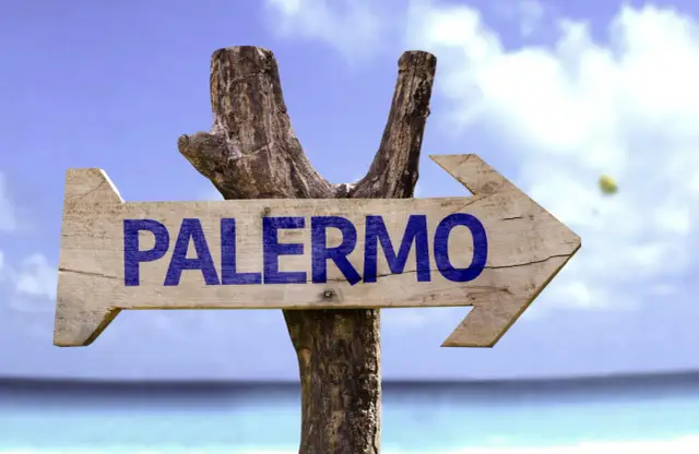 Drewniany drogowskaz "PALERMO" na tle błękitnego nieba i morza. Czas zacząć planować, ile się leci do Palermo!