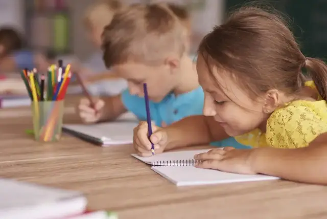 Dzieci skupione na nauce, rysują kredkami. To przykład kształcenia zintegrowanego, gdzie różne formy aktywności łączą się w procesie edukacyjnym.