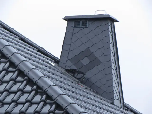 Nowy komin z obróbką struktonitem, pokryty ciemną dachówką, prezentuje się solidnie.