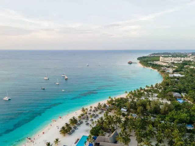 Rajska plaża na Zanzibarze z turkusową wodą, palmami i łodziami. Sprawdź atrakcyjne zanzibar ceny na wakacje marzeń!