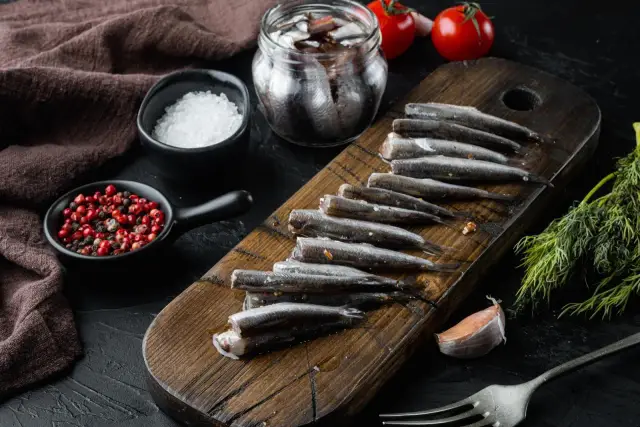 Świeże ryby, przygotowane do marynowania, to właśnie co to jest anchois. Obok sól, pieprz i czosnek.