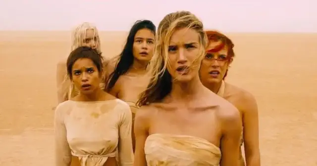 Pięć kobiet z filmu "Mad Max: Na drodze gniewu" stoi na pustyni, ich twarze wyrażają niepokój.