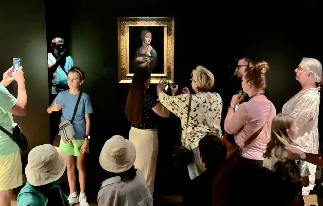 Grupa ludzi ogląda obraz "Dama z łasiczką" Leonarda da Vinci.