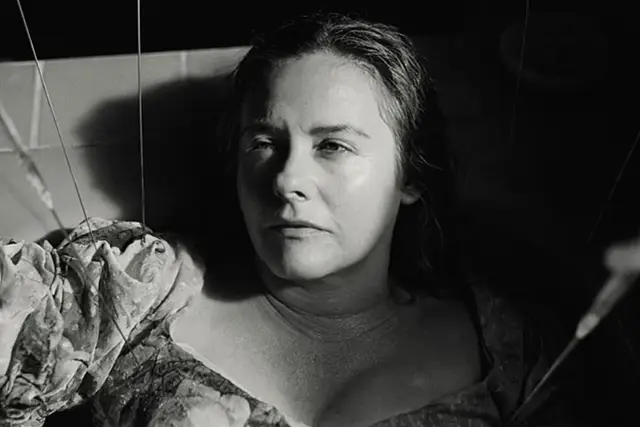 Alicia Silverstone w mrocznym kadrze, jakby marionetka w jednym z jej filmów.