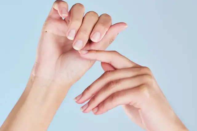 Dłonie z naturalnymi paznokciami, jedna dotyka drugiej. Zastanawiasz się nad manicure japoński wady?