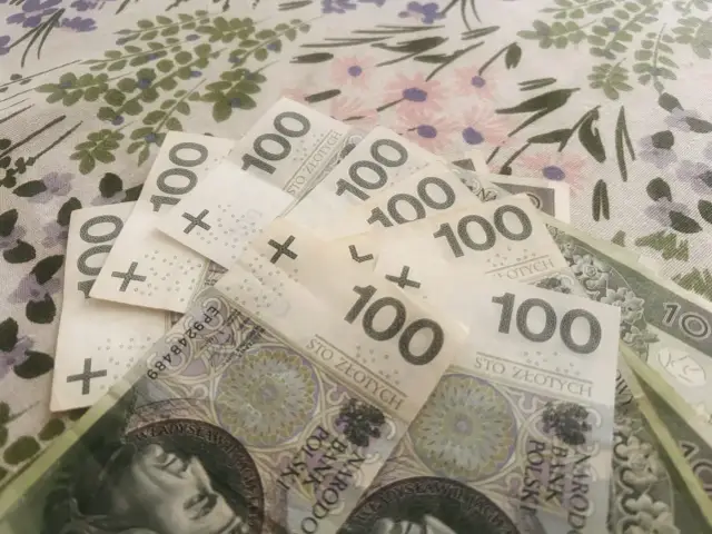 Stos banknotów 100 zł. Może to być związane z przeliczeniem emerytury nauczycielskiej na powszechną.
