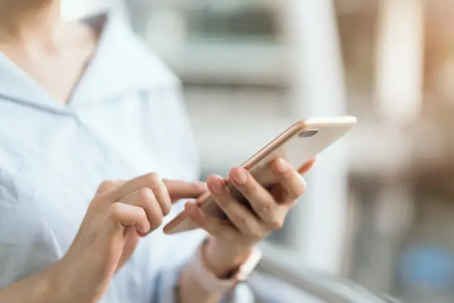 Dłonie trzymające smartfon, szukające informacji, jak wyłączyć tryb awaryjny w telefonie.