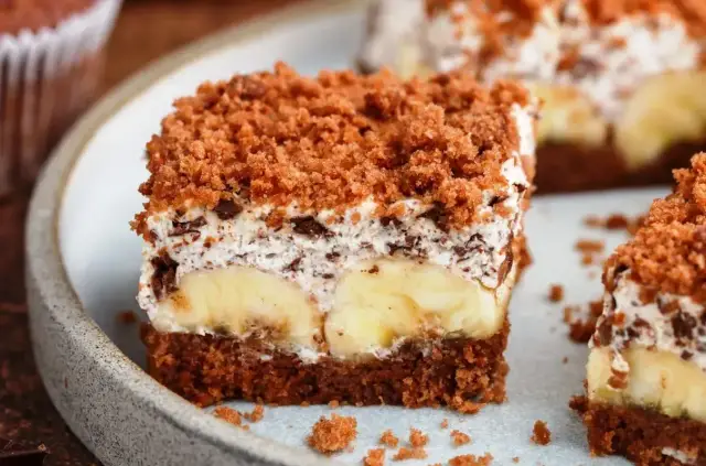 Proste ciasto bananowe z olejem i kakao, z warstwą kremu i kawałkami bananów, posypane kruszonką.