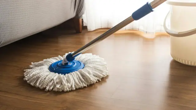 Mop na drewnianej podłodze, przygotowany do czyszczenia. Dowiedz się, jak przywrócić blask panelom podłogowym i cieszyć się ich naturalnym pięknem.