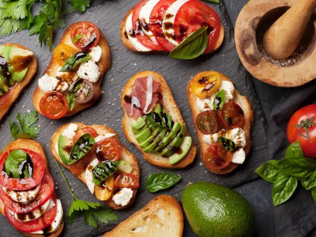 Kolorowe kanapki z pomidorami, mozzarellą, awokado i bazylią, skropione balsamicznym sosem. Idealne na letnie przyjęcie.