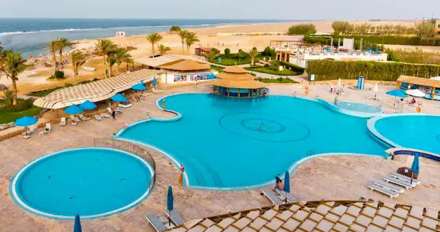 Basen w Concorde Moreen Beach Resort & Spa, z palmami i plażą w tle.