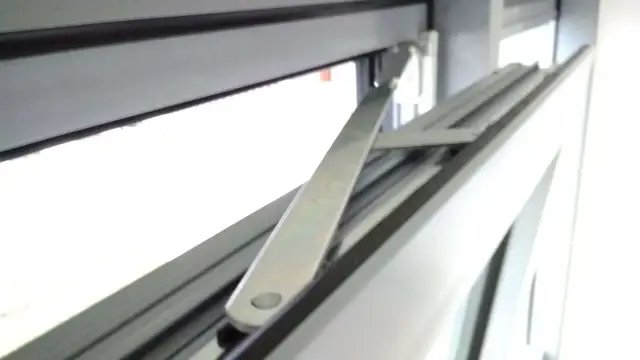 Mechanizm okna uchylnego do mycia. Metalowe ramię połączone z ramą okna, umożliwiające otwarcie skrzydła w pozycji uchylnej.