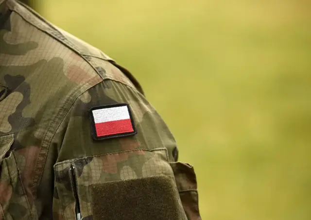 Fragment munduru żołnierza z naszywką z polską flagą. Symbol gotowości do służby, może oznaczać pobór do wojska.