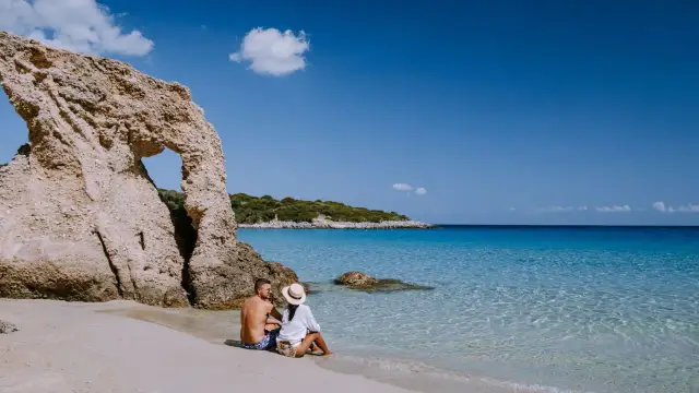 Para na plaży na Sardynii, majowa pogoda idealna na relaks przy krystalicznie czystej wodzie i skalnych formacjach.