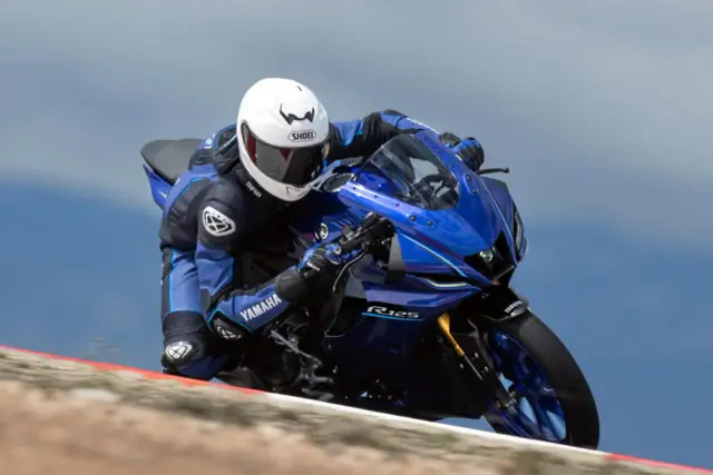 Motocyklista w kombinezonie Yamahy pochyla się na torze na sportowym motocyklu Yamaha YZF-R125. Dane techniczne tego modelu są imponujące.