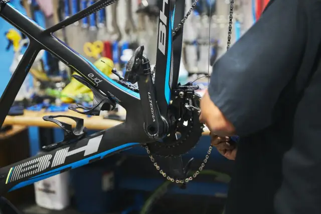 Mechanik dokonuje regulacji przedniej przerzutki w rowerze szosowym.