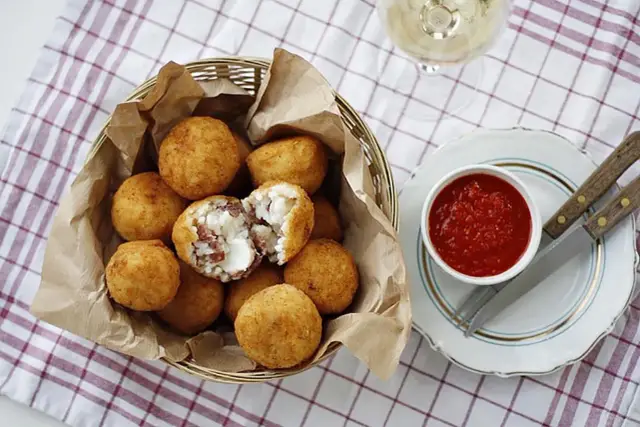 Koszyk pełen chrupiących arancini, czyli smażonych kulek ryżowych z serem i wędliną. Idealne na przekąskę!