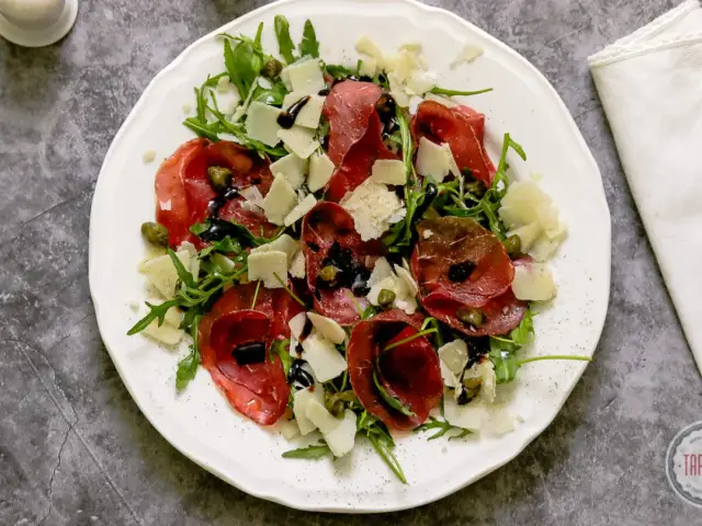 Sałatka z bresaolą, rukolą, parmezanem i kaparami, polana sosem balsamicznym. Tak wygląda pyszna bresaola, co to jest?