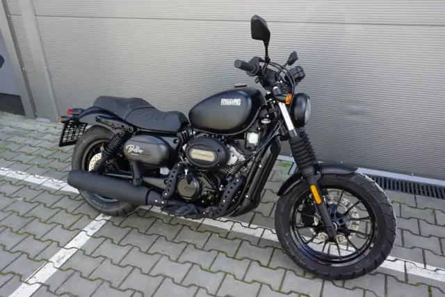Czarny motocykl Hyosung GV125S Bobber stoi na kostce brukowej.