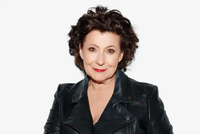 Dorota Kolak w skórzanej ramonesce, z burzą brązowych włosów i czerwoną szminką. Aktorka znana z wielu filmów.