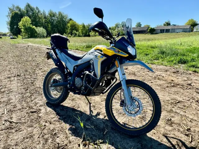 Żółto-szary motocykl typu adventure, gotowy do podboju terenu. Ten **dominar** dróg i bezdroży czeka na przygodę.