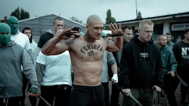 Grupa mężczyzn, jeden z tatuażem "Furioza 3", przygotowuje się do konfrontacji.