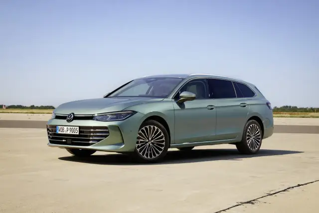 Nowy Volkswagen Passat B9 w kolorze zielonym, zaparkowany na betonowej nawierzchni, z błękitnym niebem w tle.