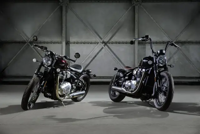 Dwa motocykle Triumph Bobber, jeden w kolorze bordowym, drugi czarny, stoją w industrialnym wnętrzu.
