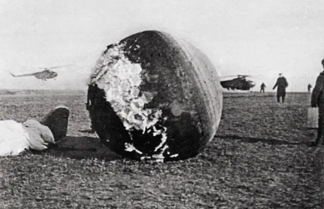 Kapsuła po pierwszym locie w kosmos. W tle lądujące helikoptery i ludzie.
