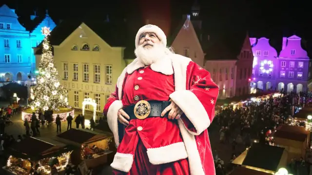 Święty Mikołaj na jarmarku bożonarodzeniowym w Olsztynie, w tle choinka i kolorowo oświetlone kamienice.