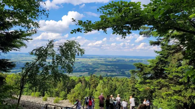 Widok na dolinę, gdzie w oddali wije się rzeka Słupia. Grupa turystów podziwia krajobraz z punktu widokowego.