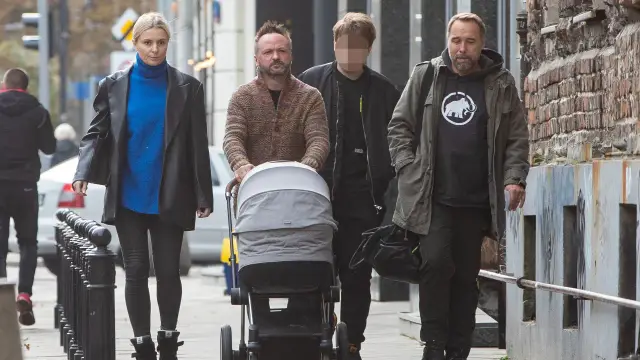 Marcin Kindla z rodziną spaceruje z wózkiem. Dzieci są w wózku, a dorośli idą obok.