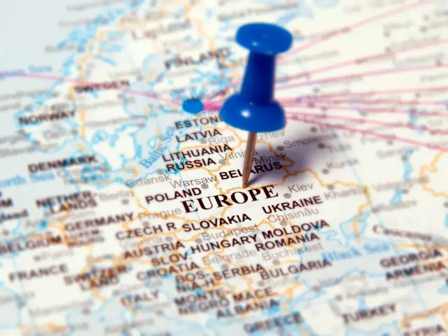 Mapa Europy z pinezką wbita w słowo "EUROPE". Widoczne stolice krajów Europy, takie jak Warszawa, Praga, Wiedeń, Budapeszt, Kijów.