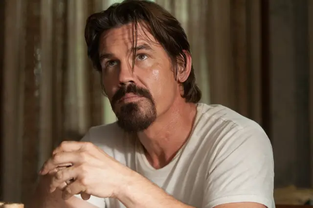 Josh Brolin w białej koszulce, z charakterystyczną brodą, wygląda jak postać z jednego z jego filmów.