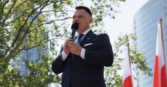 Sławomir Mentzen przemawia na tle drzew i nowoczesnego budynku, mówiąc o swoim majątku.