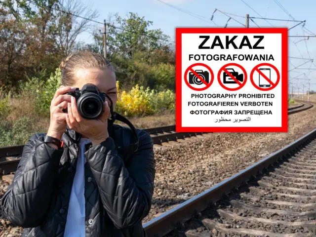 Kobieta z aparatem przy torach kolejowych, ignoruje znak "ZAKAZ FOTOGRAFOWANIA".