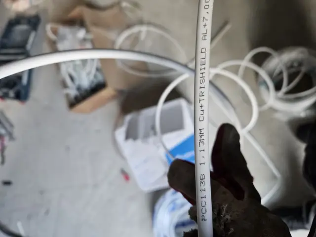 Rękawica trzyma biały kabel antenowy z oznaczeniami. Czy kabel antenowy ma znaczenie? Tak, jakość wpływa na sygnał.