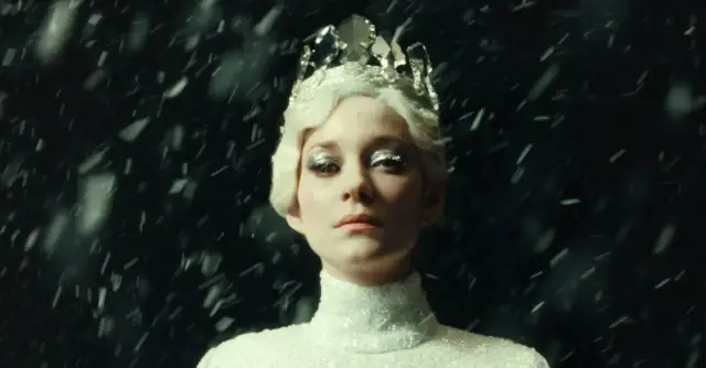 Marion Cotillard w koronie i błyszczącej sukni, otoczona śniegiem, jak z jej filmów.